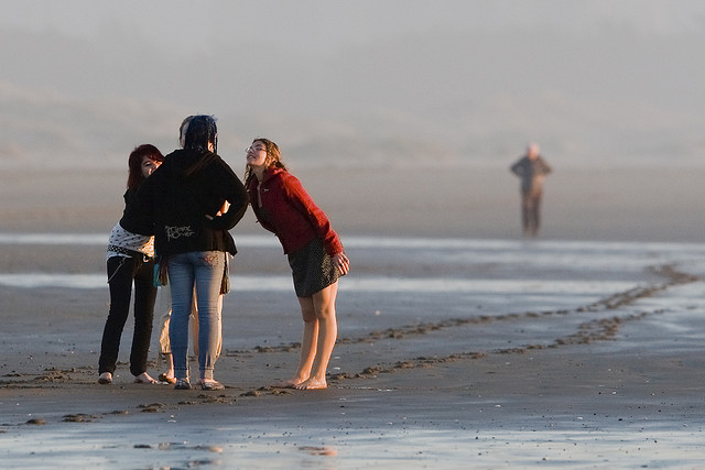 "Four young female girls conversing and cavorting on the Morro Strand State Beach", obra de Mike Baird